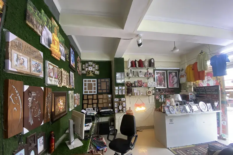 Inside the shop: frames on the green wall, cushions and mugs on the shelves, the counter at the back.