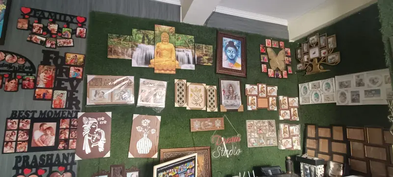 Collage frames, canvas panels and wooden wall pieces on the green display wall inside the shop.