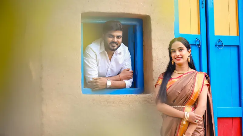 Couple photographed at a painted blue window on a village wall.